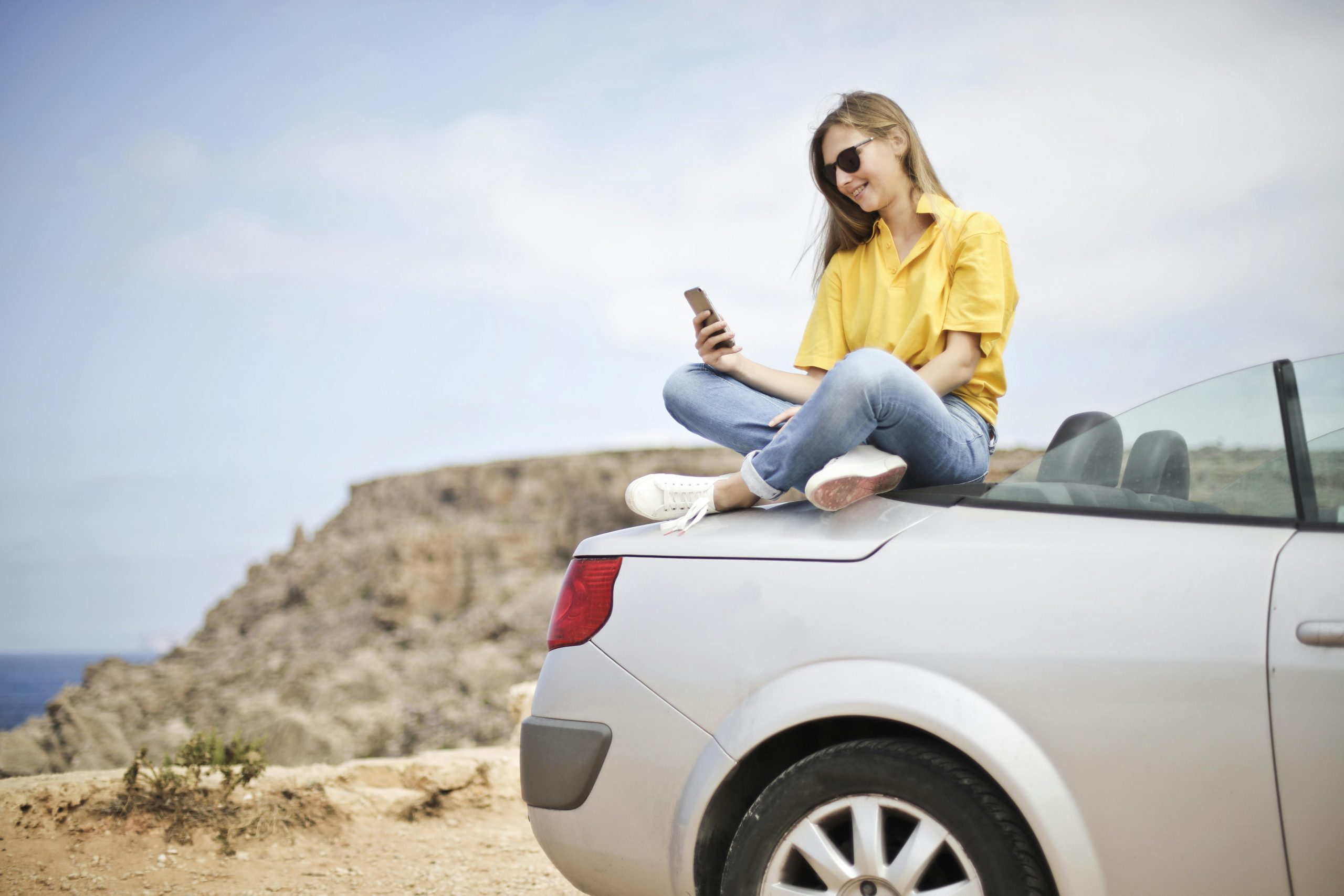 lady sitting on a car using her phone for roaming